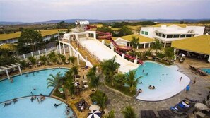 Un parc aquatique doté de plusieurs piscines, de toboggans et d’un grand bâtiment à toit plat.