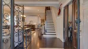 A spacious hallway with a wooden staircase, a kitchen area, and a dining space.