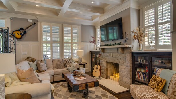A cozy living room with a fireplace, a sofa, a coffee table, and a guitar.