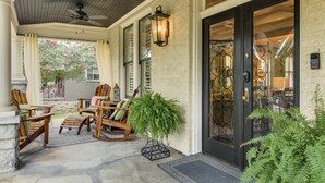 A covered porch with wooden chairs and a potted plant.