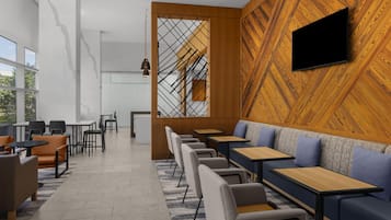 A modern interior with seating areas, tables, and a TV mounted on a wooden wall.