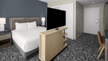 Een hotelkamer met een bed, een televisie op een standaard, een bureau en een stoel.