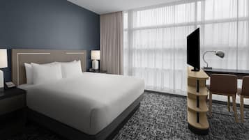 Una habitación de hotel con una cama grande, un escritorio con computadora y televisión.