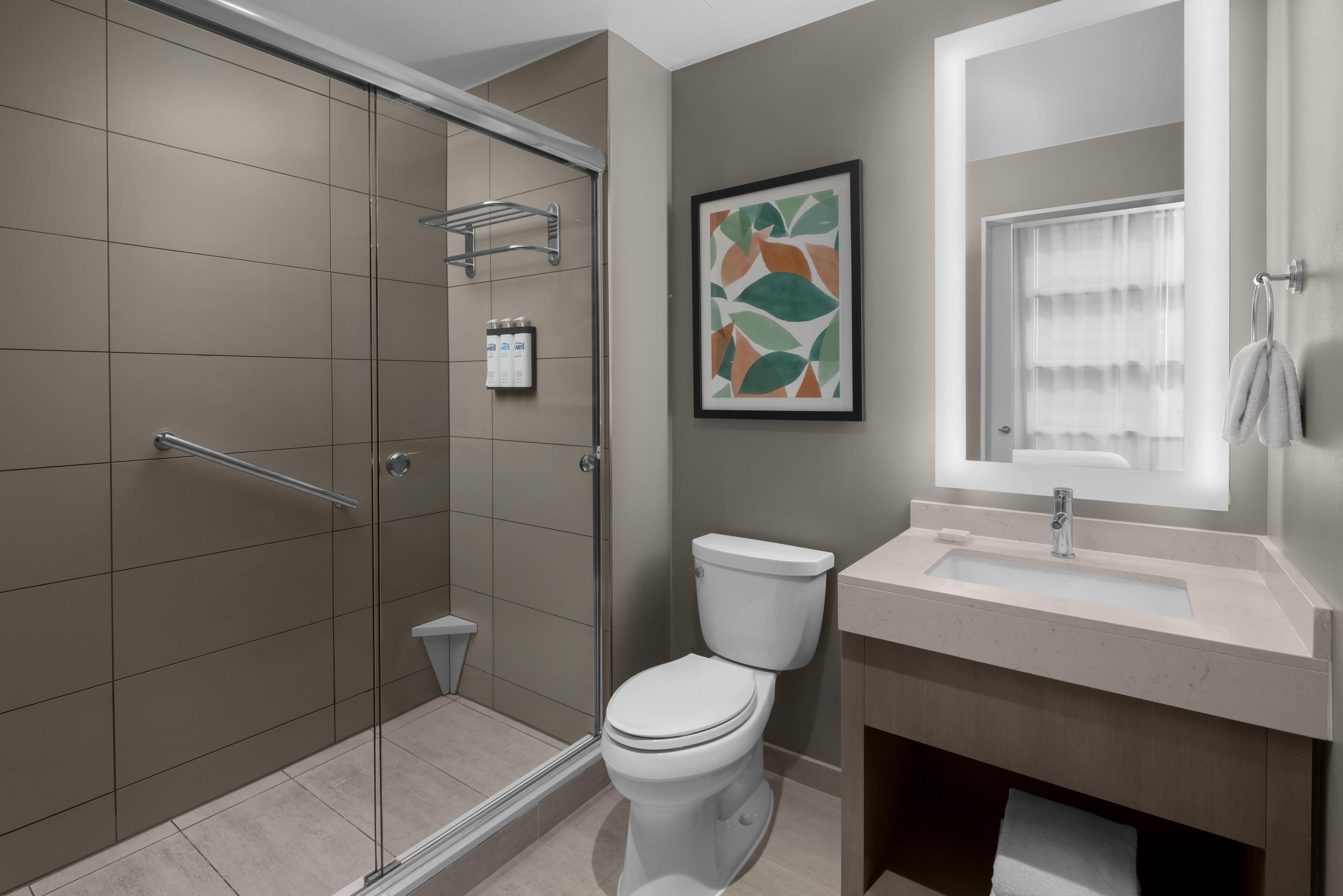 A modern bathroom with a shower, toilet, and sink.