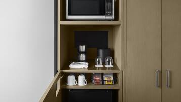 A kitchenette with a microwave, coffee maker, and tea bags.