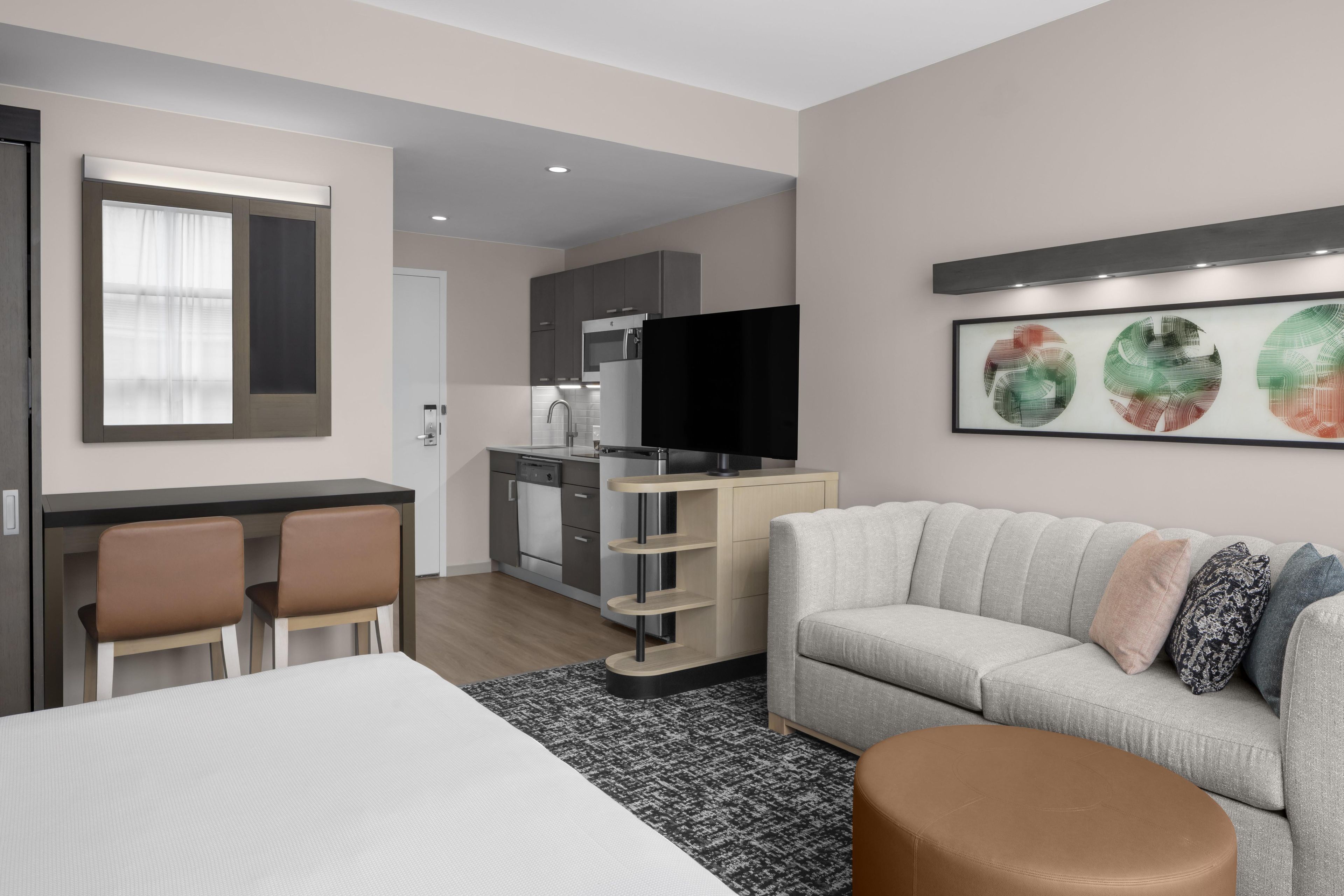 Una habitación de hotel moderna con cama, sofá, comedor y cocina.