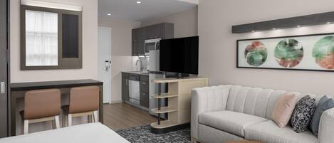 Una habitación de hotel moderna con cama, sofá, comedor y cocina.