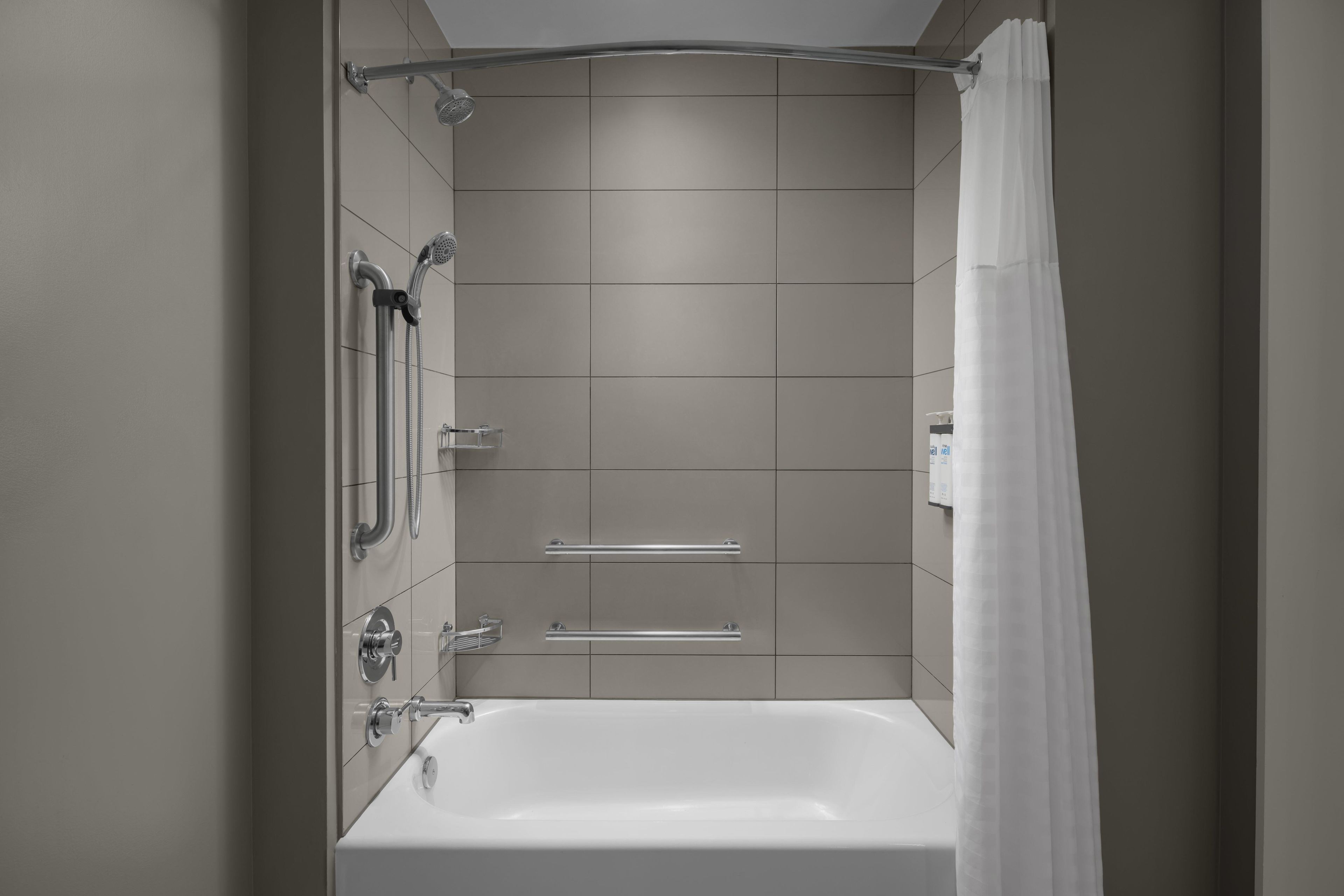 Un baño moderno con bañera, ducha y barras de apoyo.