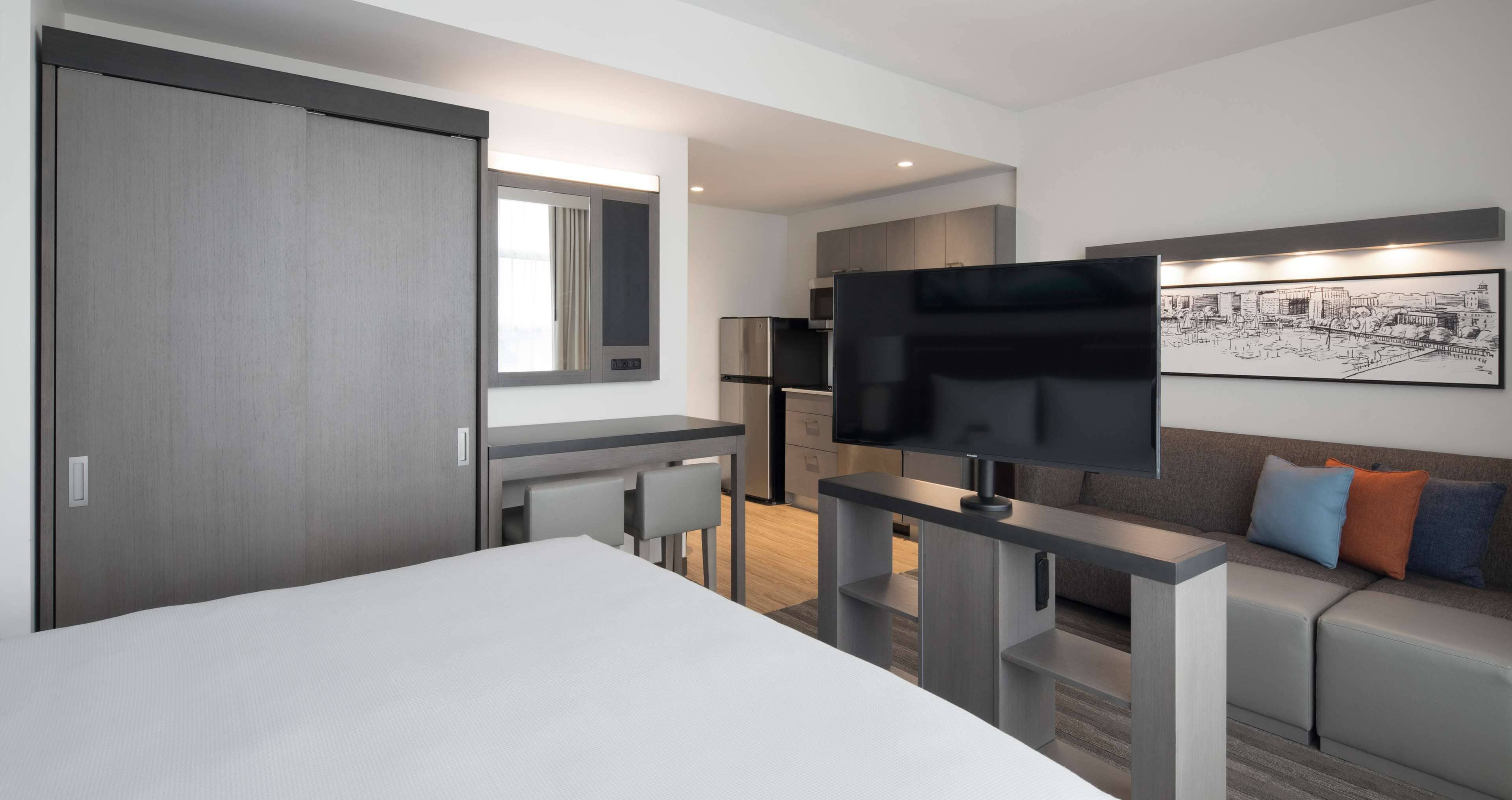 Una habitación de hotel moderna con una cama, un escritorio, un televisor y un sofá.