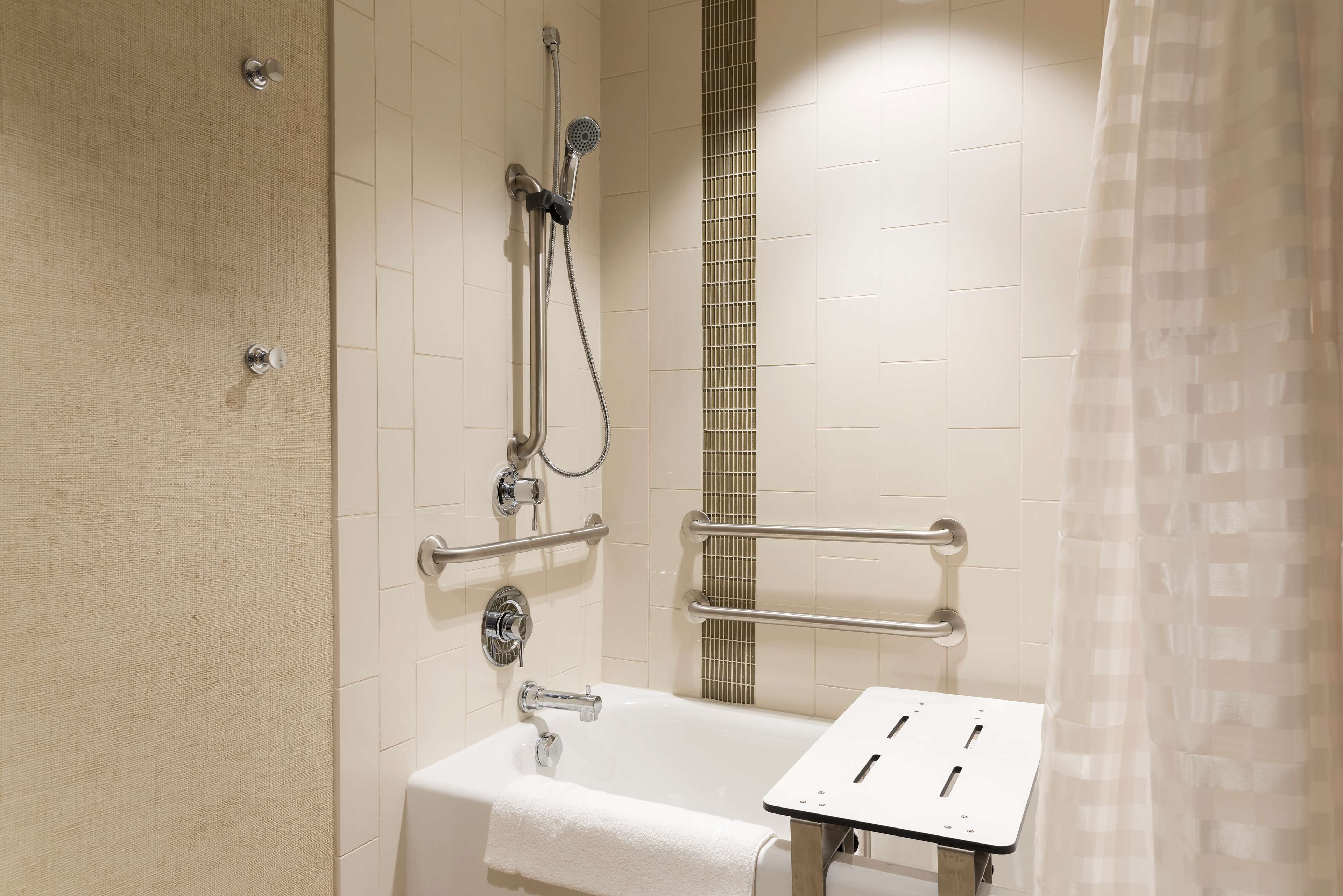 A bathroom with a bathtub, a shower, and grab bars.