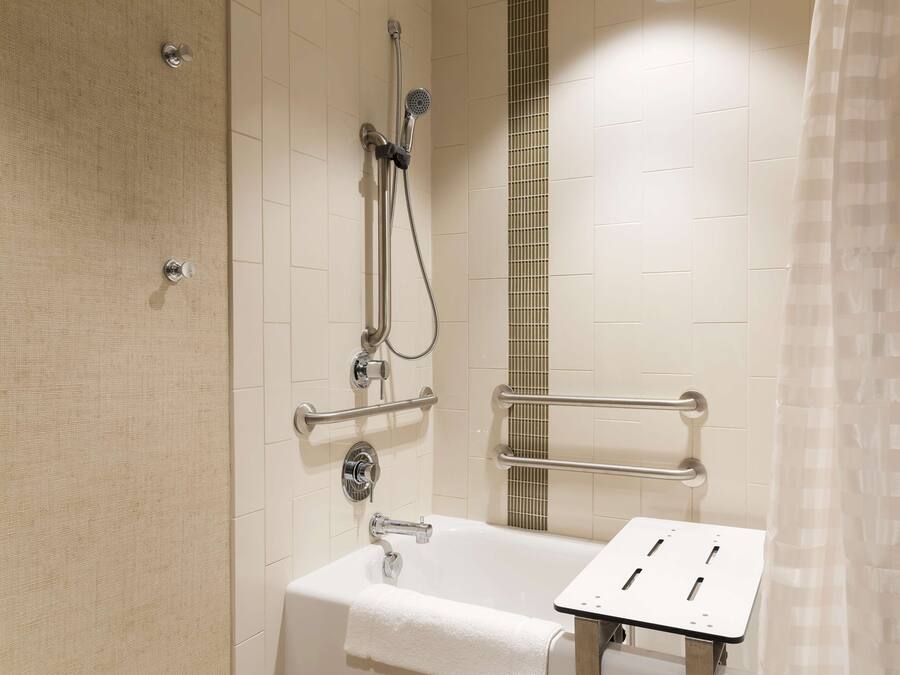 Une salle de bain équipée d’une baignoire, d’une douche et de barres d’appui.