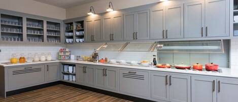 Una cocina moderna con armarios grises, suelo de madera y una isla central con vitrina de cristal.
