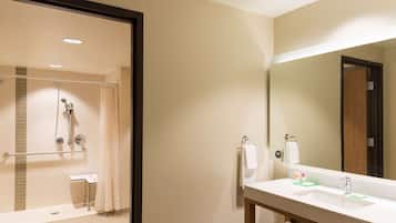 Un baño moderno con ducha, lavamanos y espejo.