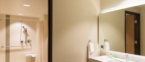 A modern bathroom with a shower, a sink, and a mirror.