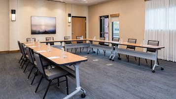 A conference room with a long table, chairs, and a large screen.