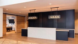 Un área de recepción moderna con suelo de madera, un mostrador y dos lámparas colgantes.