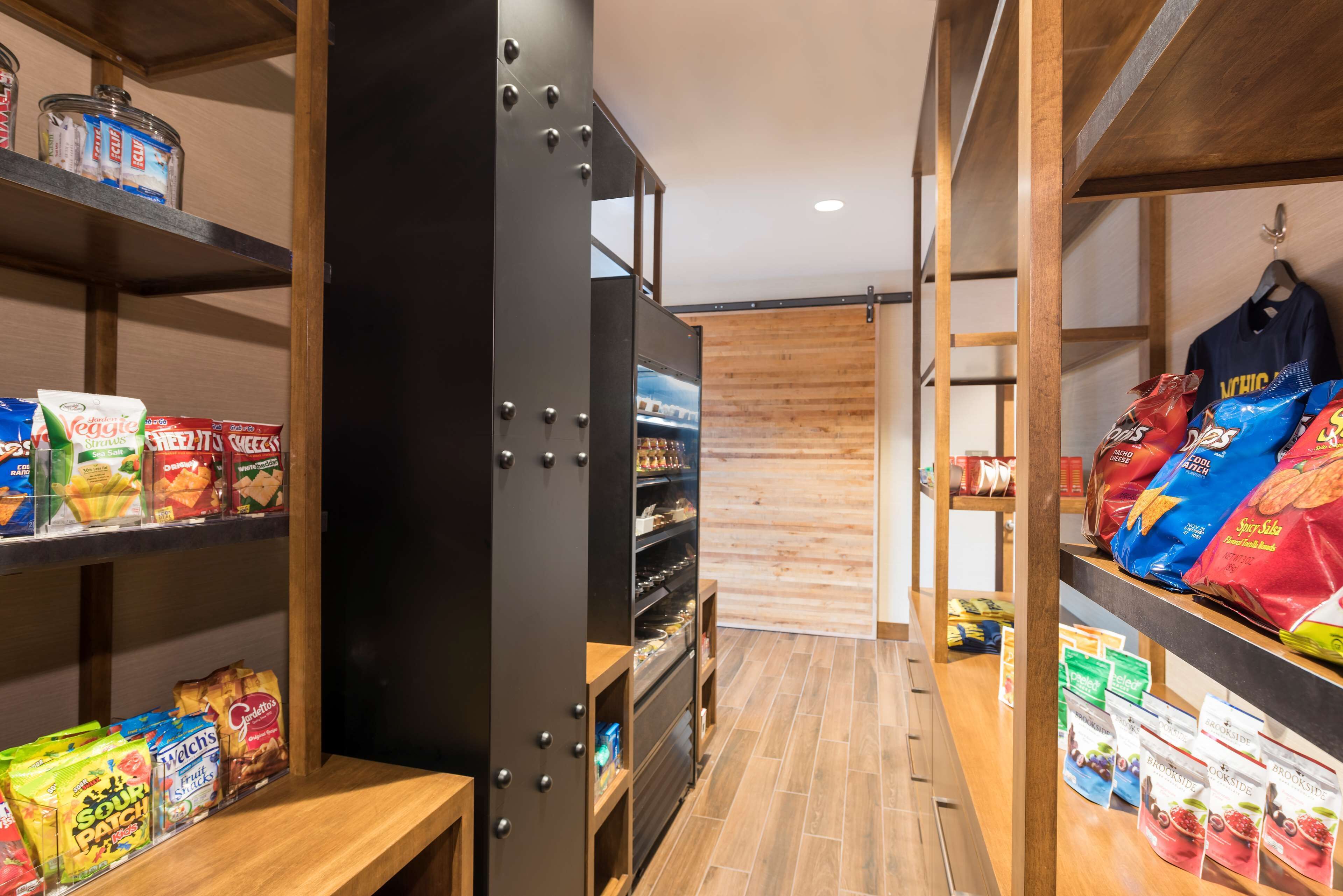 A narrow aisle with shelves on either side stocked with snacks and packaged goods.