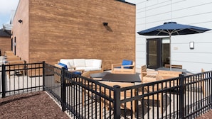Un espacio al aire libre con mobiliario de madera y una cerca de metal negro.