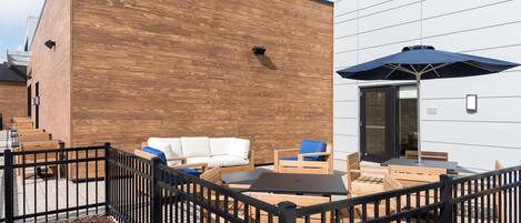 Un espacio al aire libre con mobiliario de madera y una cerca de metal negro.