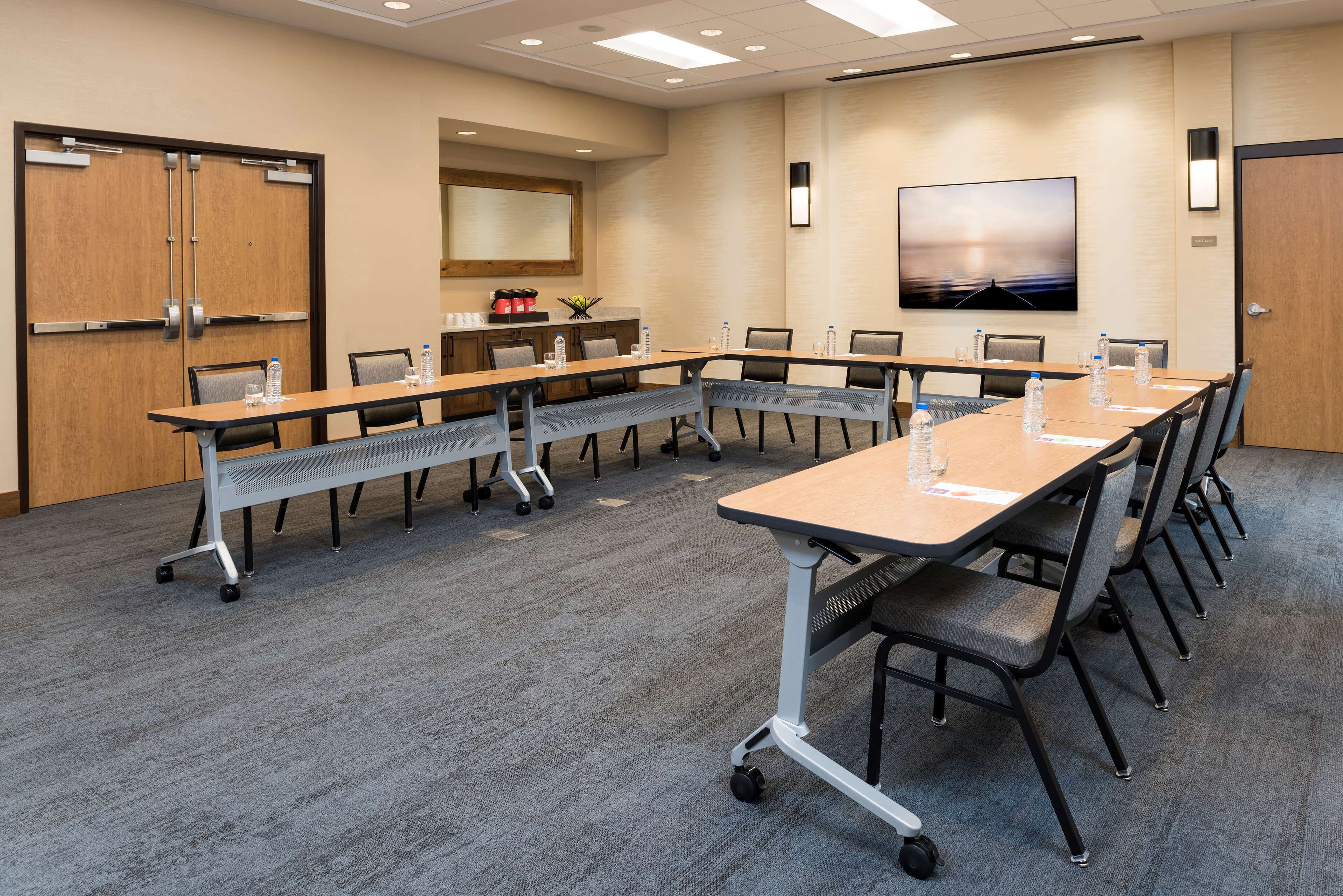 A conference room with a long table, chairs, and a carpeted floor.