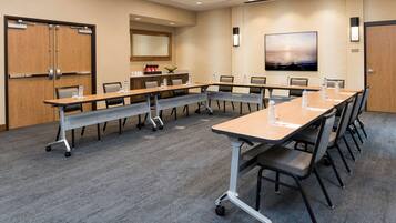 A conference room with a long table, chairs, and a carpeted floor.