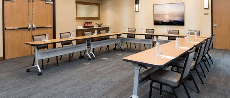 A conference room with a long table, chairs, and a carpeted floor.