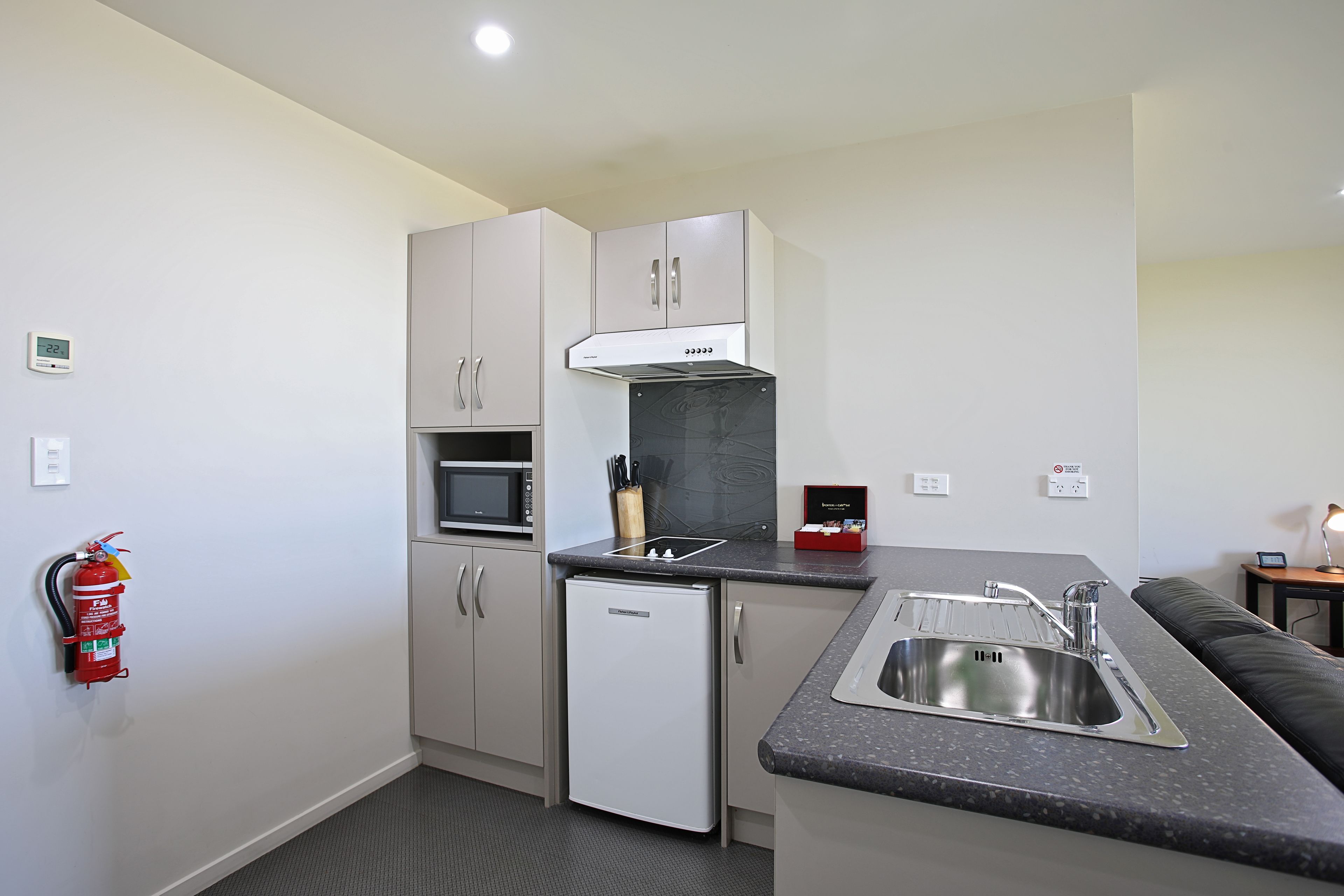 A compact kitchen with a microwave, a built-in oven, a dishwasher, and a sink.
