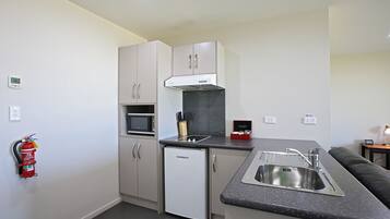 A compact kitchen with a microwave, a built-in oven, a dishwasher, and a sink.