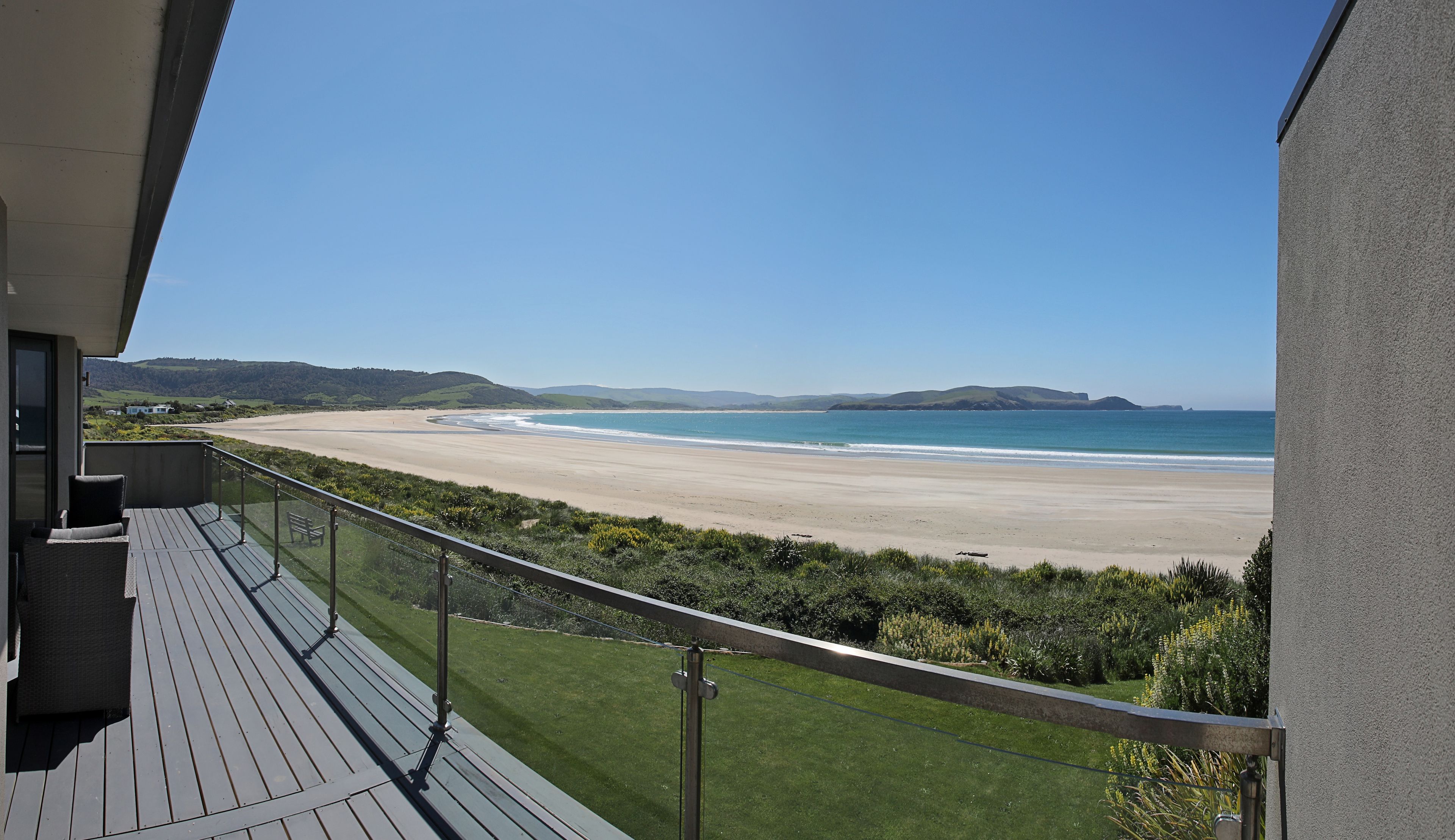 Ein Balkon mit Blick auf einen Strand und sanfte Hügel in der Ferne.