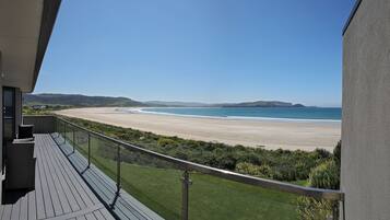 Ein Balkon mit Blick auf einen Strand und sanfte Hügel in der Ferne.