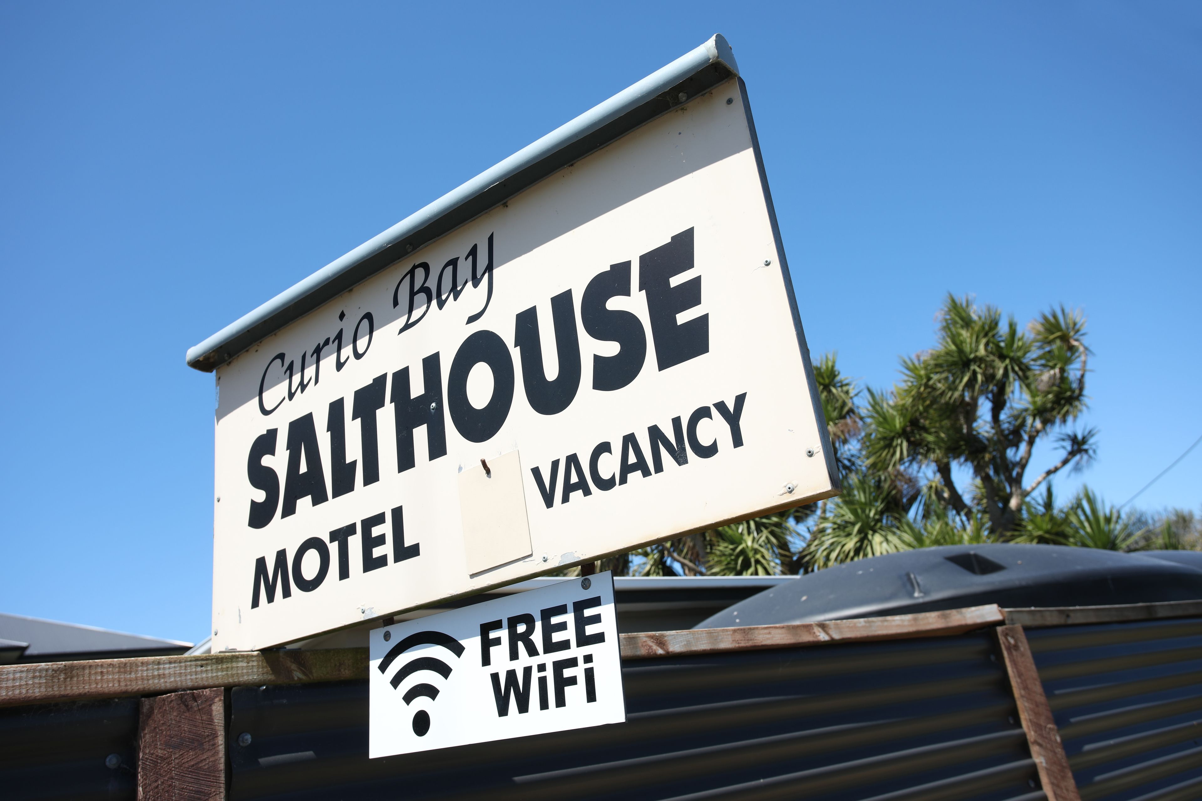 A sign for Curio Bay Salhouse Motel advertising a vacancy and free WiFi.
