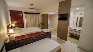 Una camera d'albergo con un letto, un comodino, una lampada e un bagno con uno specchio e un lavandino.
