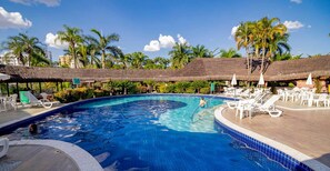A swimming pool with lounge chairs and umbrellas, surrounded by palm trees and a clear sky. - Hot Springs - JC Temporada (Caldas Novas)