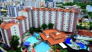 Un hotel di grandi dimensioni con diverse piscine, un bar panoramico e una vegetazione rigogliosa.