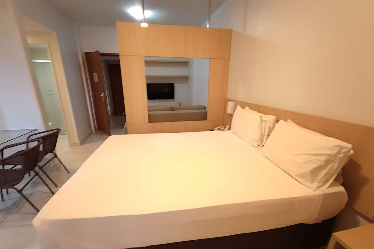 A hotel room with a large bed, a desk, and a chair.