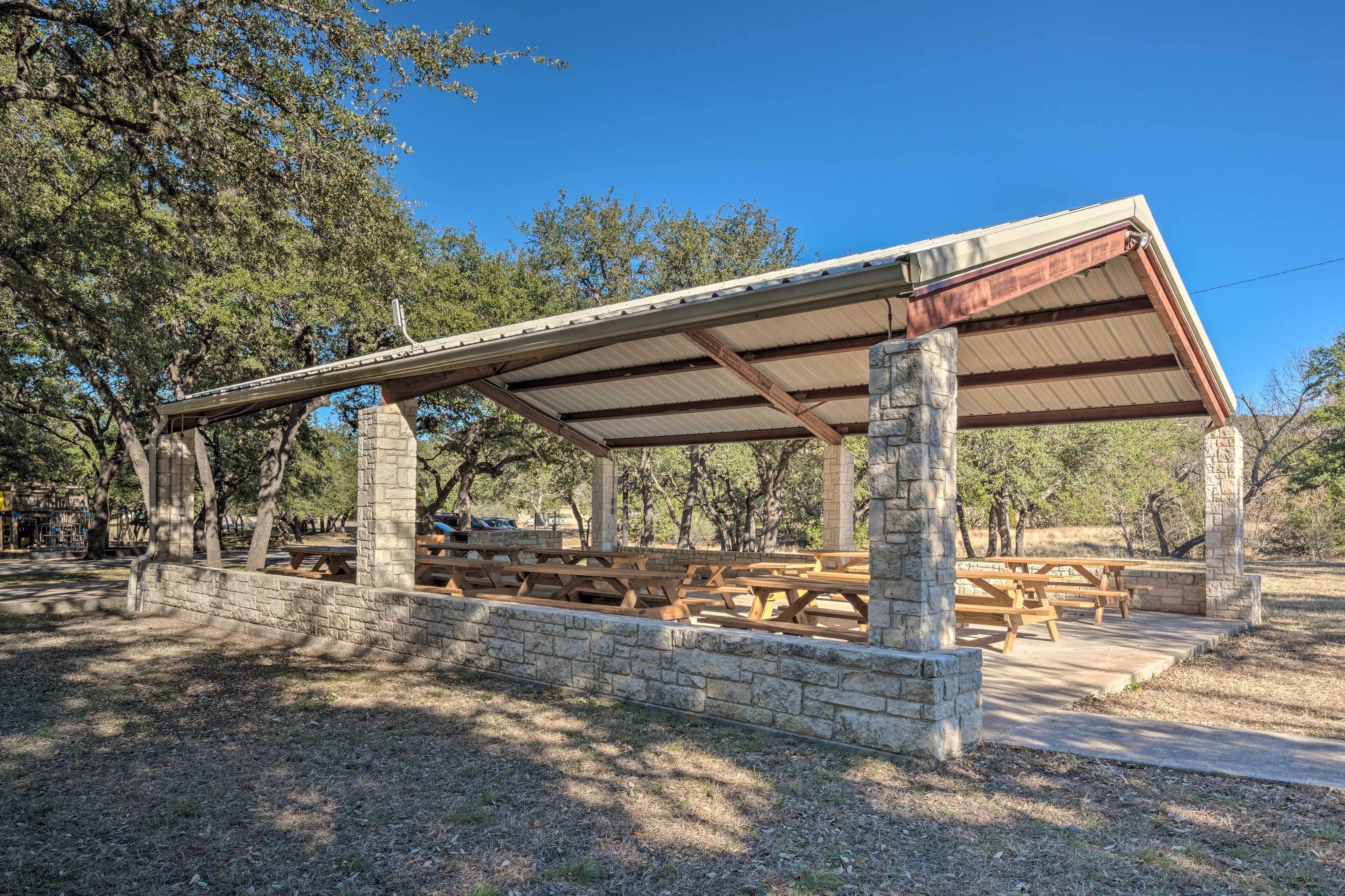 A covered picnic area with stone columns and wooden benches.