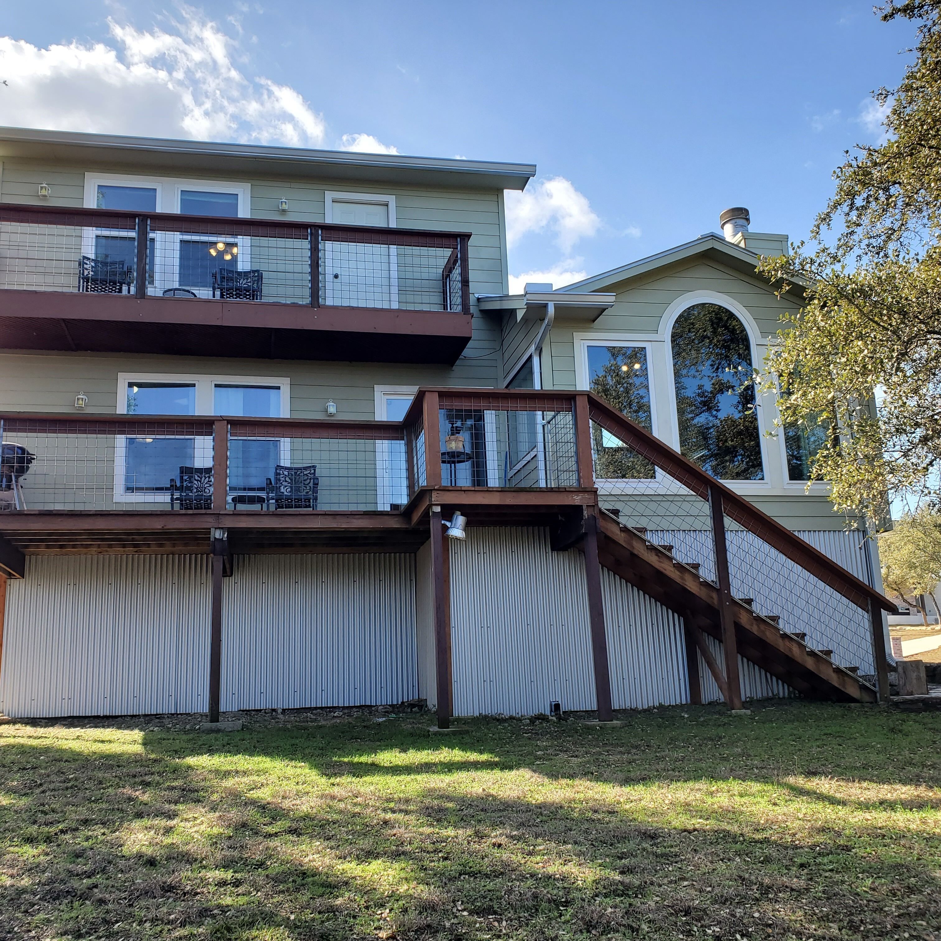 A two-story house with a covered patio, a fenced yard, and a large arched window.