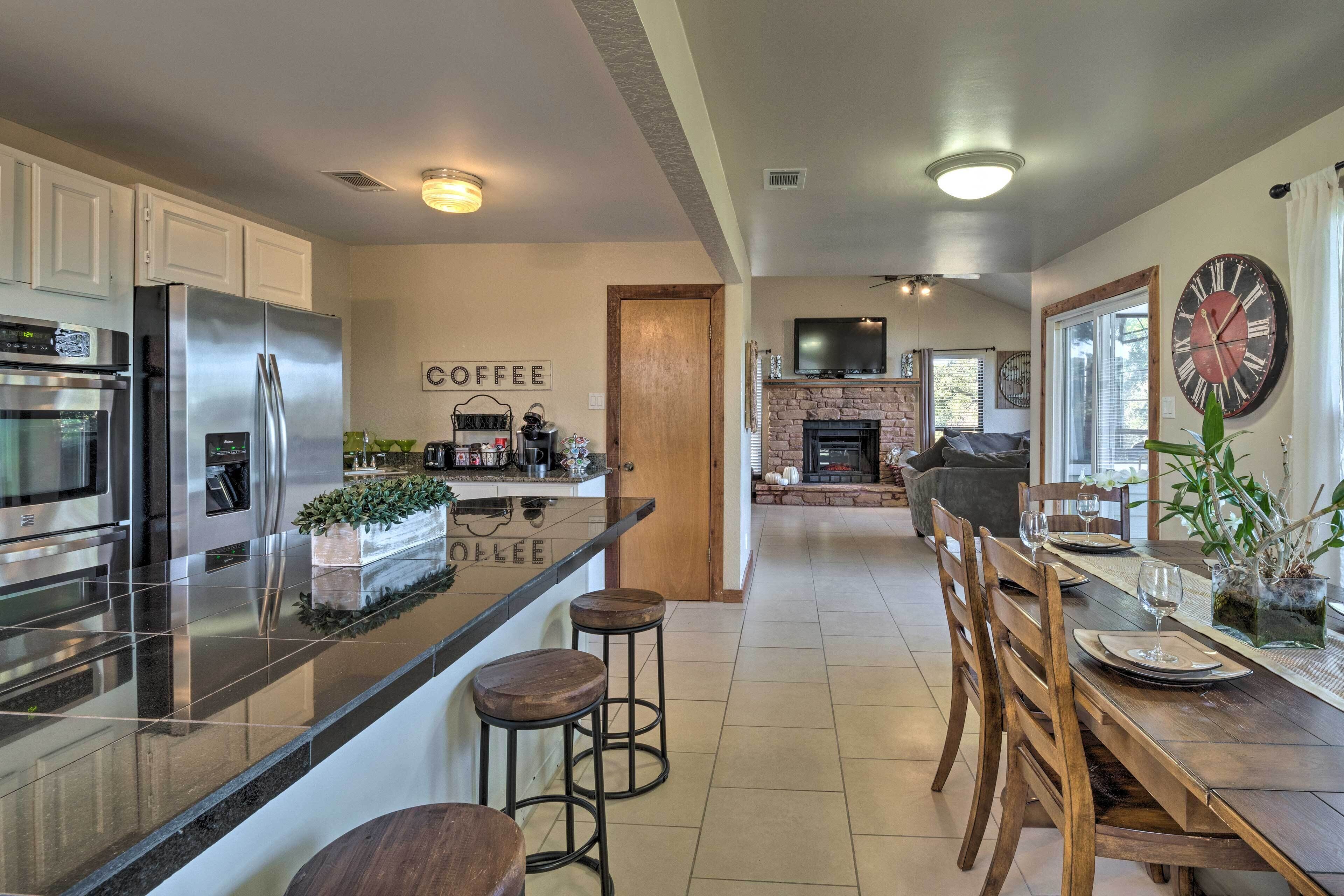 Una cocina moderna con electrodomésticos de acero inoxidable, una barra de café y un comedor con sillas de madera y una mesa dispuesta para dos personas.