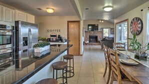 Una cocina moderna con electrodomésticos de acero inoxidable, una barra de café y un comedor con sillas de madera y una mesa dispuesta para dos personas.