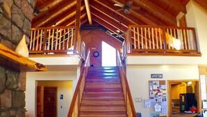 A wooden staircase leading to a second-floor balcony with a stone wall on one side. -  SWEET, IMPECCABLE CABIN IN THE PINES ! HIKING, LAKES! (Show Low)