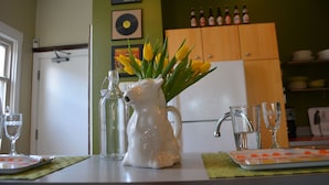 Een keukentafel met een karaf, glazen en een schaal aardbeien.