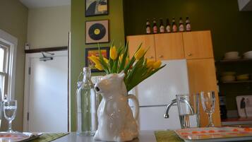 A kitchen counter with a pitcher, glasses, and a tray of strawberries.
