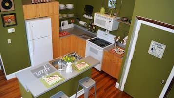 A compact kitchen with a refrigerator, stove, microwave, and wooden cabinets. There is a small dining area with a table and chairs.