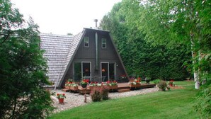 Una casa moderna con techo inclinado, rodeada de un jardín cuidado con diversas plantas y flores.