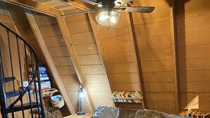 Un dormitorio con cama, un escritorio, una silla y una escalera de caracol.
