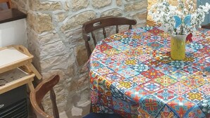 A rustic stone wall with a 'Keep Calm & Drink Beer' sign, a wine bottle decoration, and a table with a colorful tablecloth and a vase of flowers. - Chocolate Box cottage. Relax and let the world go by. (Parzac)
