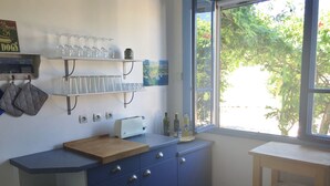 A kitchen with blue cabinets, a wooden countertop, a toaster, and a window with a view of greenery. - Rare and typical holiday house 400 m from the beach !!! (Agde)