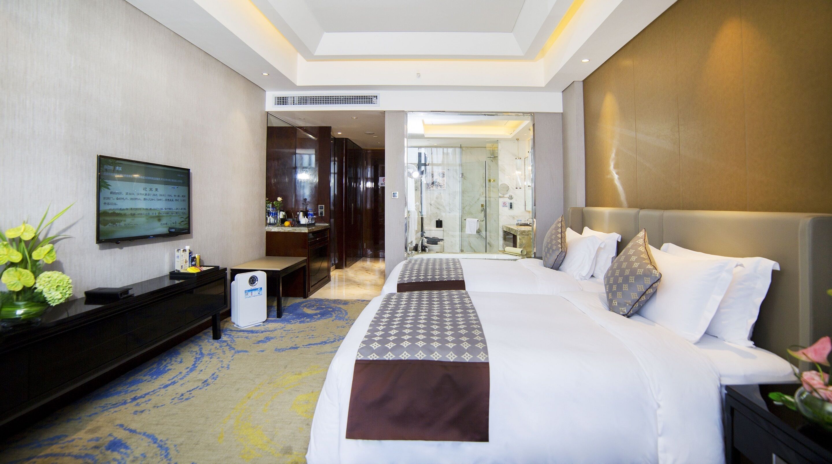 Ein Hotelzimmer mit einem großen Bett, einem Fernseher, einem Schreibtisch und einem durch eine offene Tür einsehbaren Badezimmer.