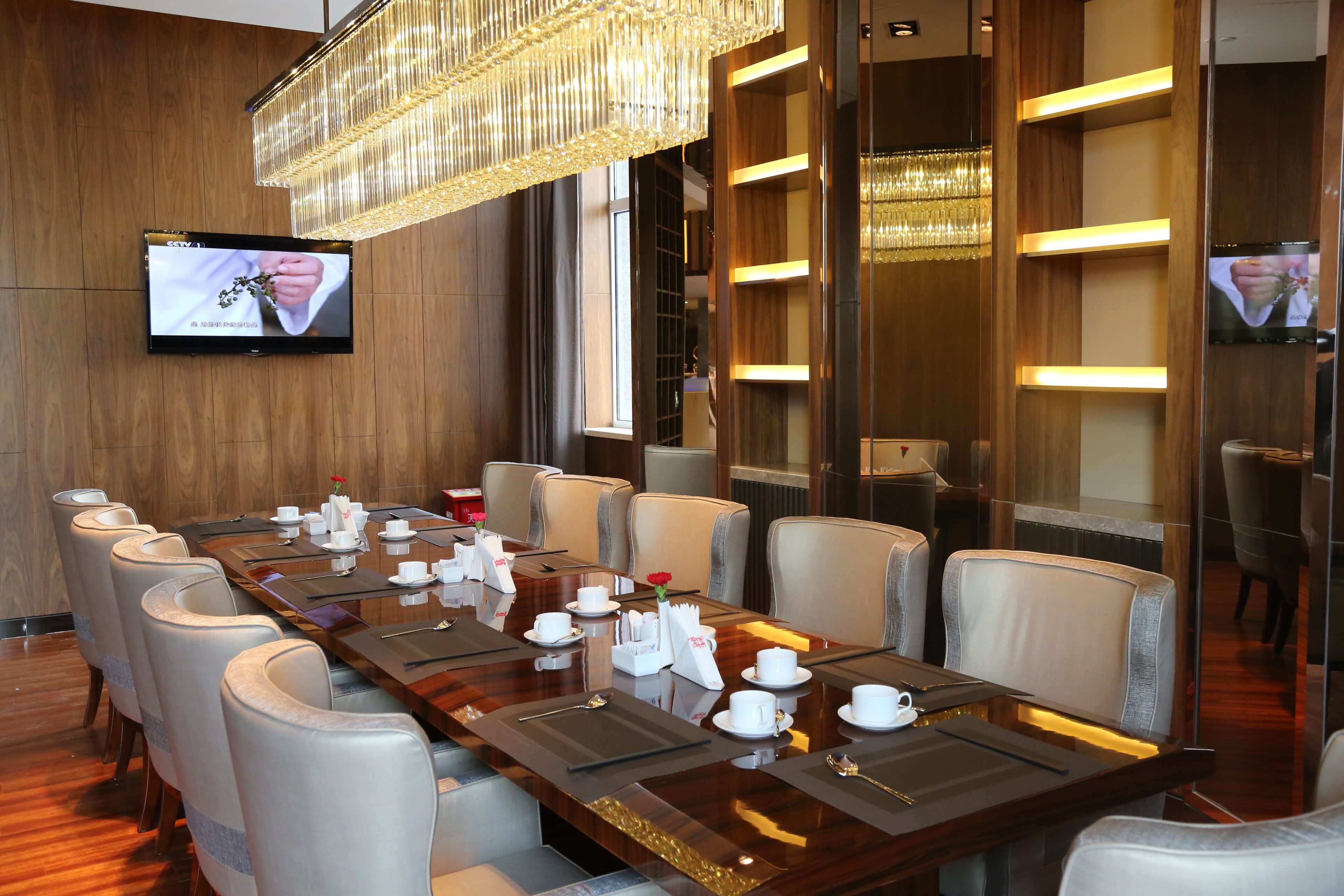 A conference room with a long table, chairs, and a TV on the wall.