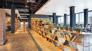 A modern library with bookshelves, seating areas, and large windows.